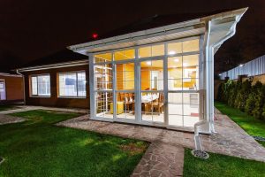 Moderne veranda tuinkamer met glazen schuifdeuren, minimalistisch design en natuurlijke materialen voor een naadloze binnen-b